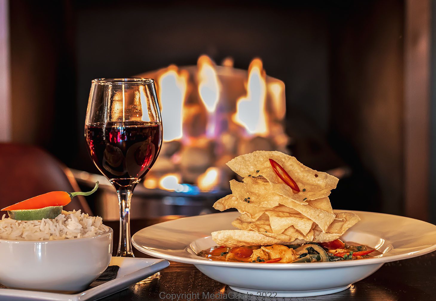 Red Thai curry plated with a glass of wine